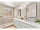 Modern bathroom featuring a double sink vanity, large mirrors, and a glass block window above the shower at 2227 Garden City Ave, Henderson, NV 89052