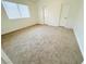 Bright bedroom with neutral carpet, large window, and two entry doors at 5040 Jacarilla Ln, North Las Vegas, NV 89031