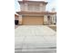 Two-story tan home with an attached two-car garage and mature landscaping in front of the house at 5040 Jacarilla Ln, North Las Vegas, NV 89031