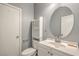 Clean bathroom with a large round mirror, white vanity, and modern fixtures at 5232 Pendergrass St, North Las Vegas, NV 89081