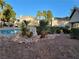 Community pool with a nearby lounge area, palm trees, and landscaped grounds at 5710 E Tropicana Ave # 1172, Las Vegas, NV 89122