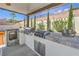 This outdoor kitchen features stainless steel appliances, a built-in grill, and an attractive tile countertop at 5855 Boulder Brook Ct, Las Vegas, NV 89149