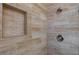 A close-up of a shower with an inset, pebble floor, and wood look tiling at 6320 Shawnee Ave, Las Vegas, NV 89107