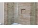 Modern shower with neutral stone look tiling and rainfall shower head at 6320 Shawnee Ave, Las Vegas, NV 89107