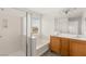 Bright bathroom featuring dual sinks, wood cabinets, a large mirror, and shower at 6480 Chebec St, North Las Vegas, NV 89084