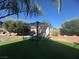 Landscaped backyard featuring manicured artificial turf, mature trees, and a shaded pergola with seating at 6756 Sea Swallow St, North Las Vegas, NV 89084