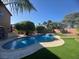 Backyard pool with water feature, mature trees, and manicured artificial turf under a clear blue sky at 6756 Sea Swallow St, North Las Vegas, NV 89084
