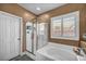 Contemporary bathroom featuring a glass-enclosed shower, soaking tub, and window with shutter style blinds at 7029 Bocaire Dr, Las Vegas, NV 89131