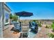 Outdoor patio with pavers, an umbrella, and seating area with a view of desert vegetation and a backyard fence at 7029 Bocaire Dr, Las Vegas, NV 89131