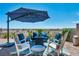 Outdoor patio with comfortable chairs, pavers, a shade umbrella, and a view of desert landscape and clear blue sky at 7029 Bocaire Dr, Las Vegas, NV 89131