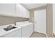 Bright laundry room with white cabinets, sink, modern washer and dryer, and access door at 7813 Riviera Beach Dr, Las Vegas, NV 89128