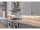 Modern kitchen featuring a stainless steel range hood, white cabinets, quartz countertops, and stainless steel appliances at 9 Rue Grimaldi Way, Henderson, NV 89011