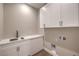 Bright laundry room with white cabinetry, quartz countertops, and modern fixtures at 9 Rue Grimaldi Way, Henderson, NV 89011