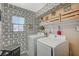 Well-lit laundry room featuring patterned wallpaper, front load washer/dryer, and overhead storage at 1413 Miller Ridge Ave, North Las Vegas, NV 89031