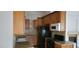 Cozy kitchen featuring brown cabinets, granite countertops, black appliances, and tiled backsplash at 1612 N Torrey Pines Dr # 104, Las Vegas, NV 89108