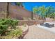 A backyard featuring a landscaped brick wall with various trees and plants at 2057 Wandering Doe Ln, Las Vegas, NV 89134