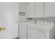 Laundry room with washer, dryer, overhead cabinets, and access to the side yard at 2699 Aldonza Dr, Henderson, NV 89014