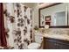 Well-lit bathroom with floral shower curtain, granite countertop, dark wood cabinets, and a large mirror at 2958 Lapis Beach Dr, Las Vegas, NV 89117