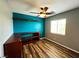 Inviting bedroom featuring modern ceiling fan, wood floors, a teal accent wall, and built-in shelving at 3412 Catherine Mermet Ave, North Las Vegas, NV 89081