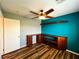 Stylish bedroom featuring hardwood floors, a ceiling fan, a teal accent wall, and a convenient closet at 3412 Catherine Mermet Ave, North Las Vegas, NV 89081