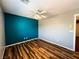 Bedroom featuring wood floors, a ceiling fan, and a bright teal accent wall at 3412 Catherine Mermet Ave, North Las Vegas, NV 89081