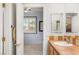 Bright bathroom with double mirrors, tiled countertops, and an open doorway to a bedroom at 3535 Coventry Gardens Dr, Las Vegas, NV 89135