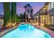 Backyard pool and patio with lush landscaping at twilight create a serene outdoor oasis for relaxation at 3535 Coventry Gardens Dr, Las Vegas, NV 89135