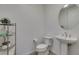 Clean powder room with a pedestal sink, modern toilet, round mirror, and decorative shelving unit at 365 Malpaso St, Las Vegas, NV 89138
