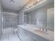 Bathroom featuring a double vanity, white marble countertops, and a tiled shower with glass doors at 420 Dakar St, Henderson, NV 89015