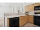 This open-concept kitchen includes wood cabinets, tiled floors, and black appliances at 4323 Village Spring St, Las Vegas, NV 89147