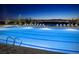 Community pool with illuminated water and lounge chairs at night at 462 Fortissimo St, Henderson, NV 89011