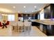 Bright kitchen featuring dark cabinets, granite countertops, an island with bar seating and stainless steel appliances at 462 Fortissimo St, Henderson, NV 89011