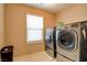 Bright laundry room features a washer and dryer with window and white tile flooring at 462 Fortissimo St, Henderson, NV 89011