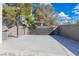 Concrete backyard sport court with basketball hoop surrounded by mature trees and a block wall for privacy at 7837 Fort Ruby Pl, Las Vegas, NV 89128