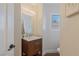 Cozy powder room with a wood vanity, mirror, and plantation shutters offering a comfortable and stylish space at 7837 Fort Ruby Pl, Las Vegas, NV 89128