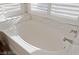 A close-up of a luxurious soaking tub situated beneath plantation shutters, offering a relaxing spa-like experience at 7837 Fort Ruby Pl, Las Vegas, NV 89128