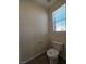 A small powder room featuring tile floors, a toilet, and a window, ideal for guests at 9312 Gold Dove Ct, Las Vegas, NV 89178