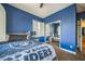 Tastefully decorated bedroom with large window and mirror closet doors, bright blue walls, and plush carpeting at 10373 Hawk Ravine St, Las Vegas, NV 89178