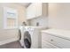 Laundry room with modern white washer and dryer, white cabinets, and plantation shutters at 190 Tall Ruff Dr, Las Vegas, NV 89148