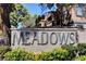 Welcome sign for the Meadows community, surrounded by vibrant landscaping and mature trees at 201 Mission Laguna Ln # 104, Las Vegas, NV 89107