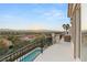 Expansive balcony with a sleek black railing showcasing panoramic views of the mountains, city, and lush greenery at 2736 Botticelli Dr, Henderson, NV 89052