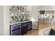 Elegant bar area with glass shelves, wine coolers, and view into the modern kitchen with stone countertops at 2736 Botticelli Dr, Henderson, NV 89052
