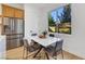 Dining area features a table, four chairs, stainless refrigerator, and a large window at 2921 Guillemot Ave, North Las Vegas, NV 89084