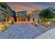 Contemporary home showcasing modern architecture, a glass garage door, and professional landscaping at dusk at 365 Crown Mesa Ave, Las Vegas, NV 89138