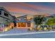 Modern home exterior at twilight with well-lit landscaping and a glass garage door at 365 Crown Mesa Ave, Las Vegas, NV 89138