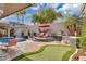 Luxurious backyard with a pool, putting green, lounge chairs, and mature palms at 4108 Royal Scots Ave, Las Vegas, NV 89141