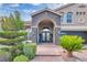 Charming home entrance with stone archway, double doors, brick walkway, and lush landscaping at 4108 Royal Scots Ave, Las Vegas, NV 89141