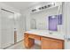 Bathroom with large mirror, wood cabinets, single sink, and glass-door shower at 5429 Sweet Shade St, Las Vegas, NV 89130
