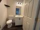 Cozy bathroom with dark floors, toilet, vanity with mirror, and door to hallway at 5591 La Perla Ct, Las Vegas, NV 89122