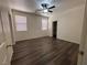 Bright bedroom with dark wood-look floors, two windows, a ceiling fan, and a closet at 5591 La Perla Ct, Las Vegas, NV 89122